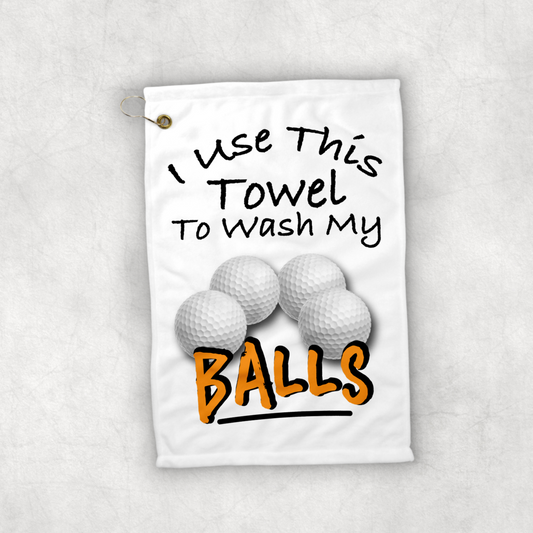 A 12x18 inch white golf towel that says in black writing Use this towel to wash my balls. With a picture of four golf balls 