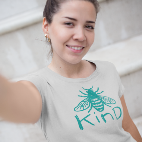 a young woman taking a morning selfie while wearing a grey t shirt with a teal coloured bee and the word kind(bee kind)